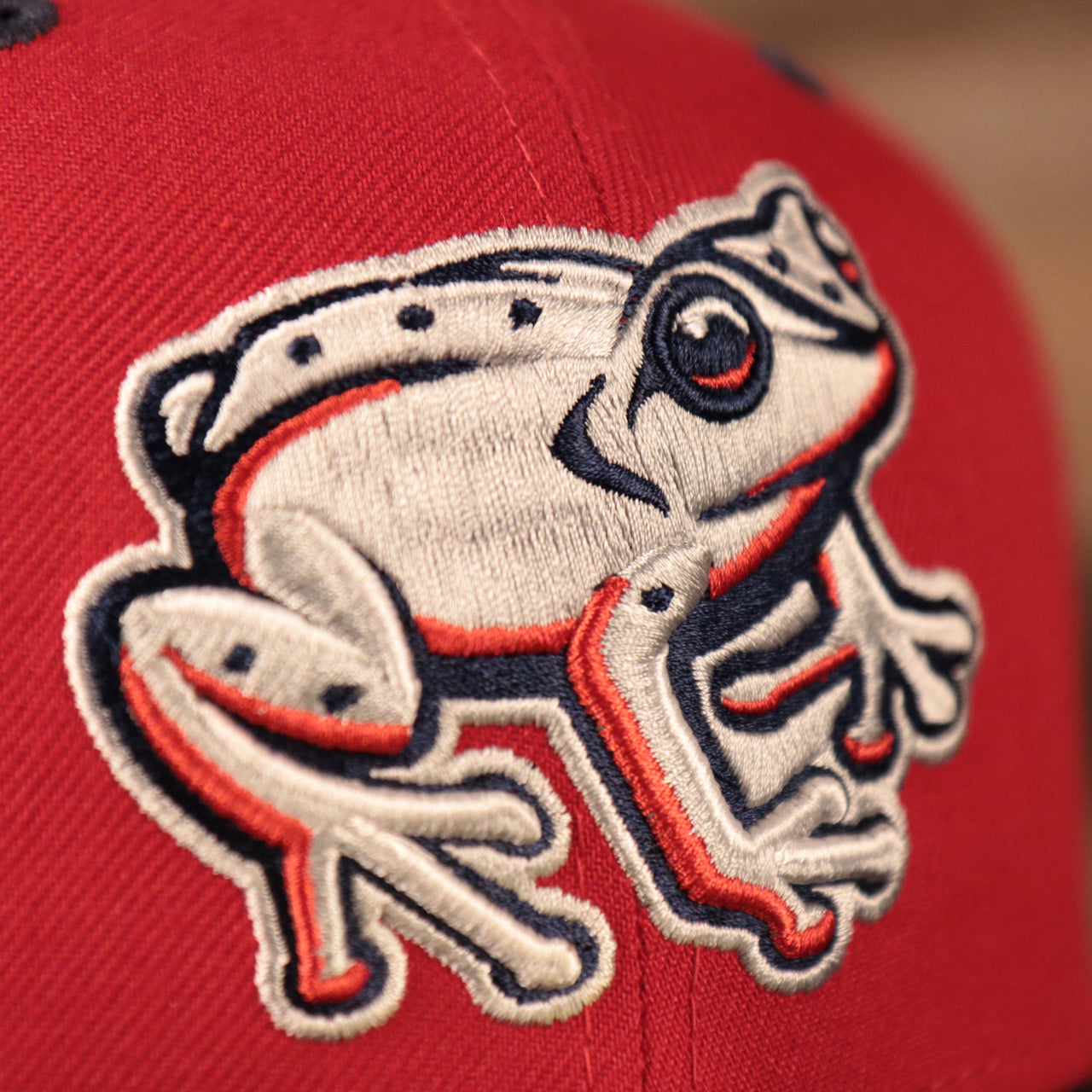 The white coquis frog logo on the front of the red coqui fitted cap for the MiLB Copa.