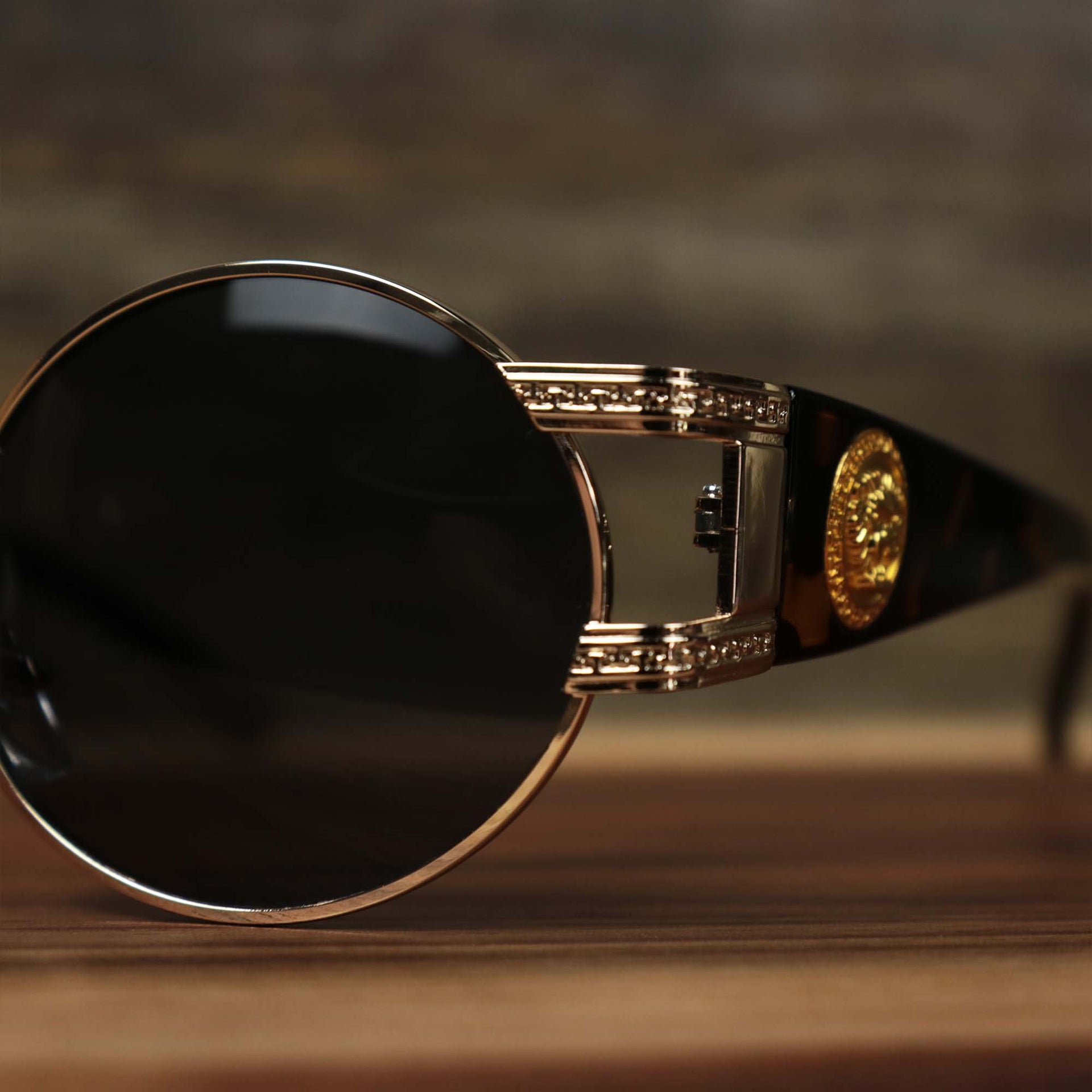 A close up of the hinge on the Circle Frame Lion Head Emblem Black Lens Sunglasses with Rose Gold Frame