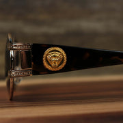 The lion head emblem on the Circle Frame Lion Head Emblem Black Lens Sunglasses with Rose Gold Frame