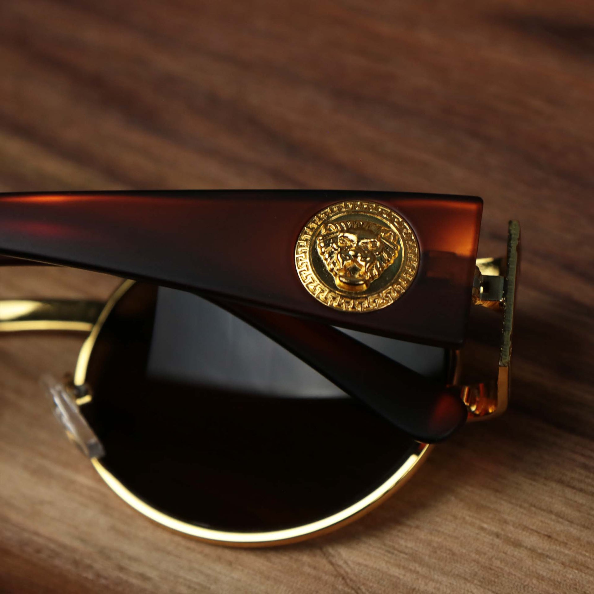 The lion head emblem on the Circle Frame Lion Head Emblem Brown Lens Sunglasses with Gold Frame