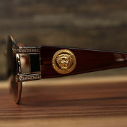 A close up of the lion head emblem on the Circle Frame Lion Head Emblem Brown Lens Sunglasses with Rose Gold Frame