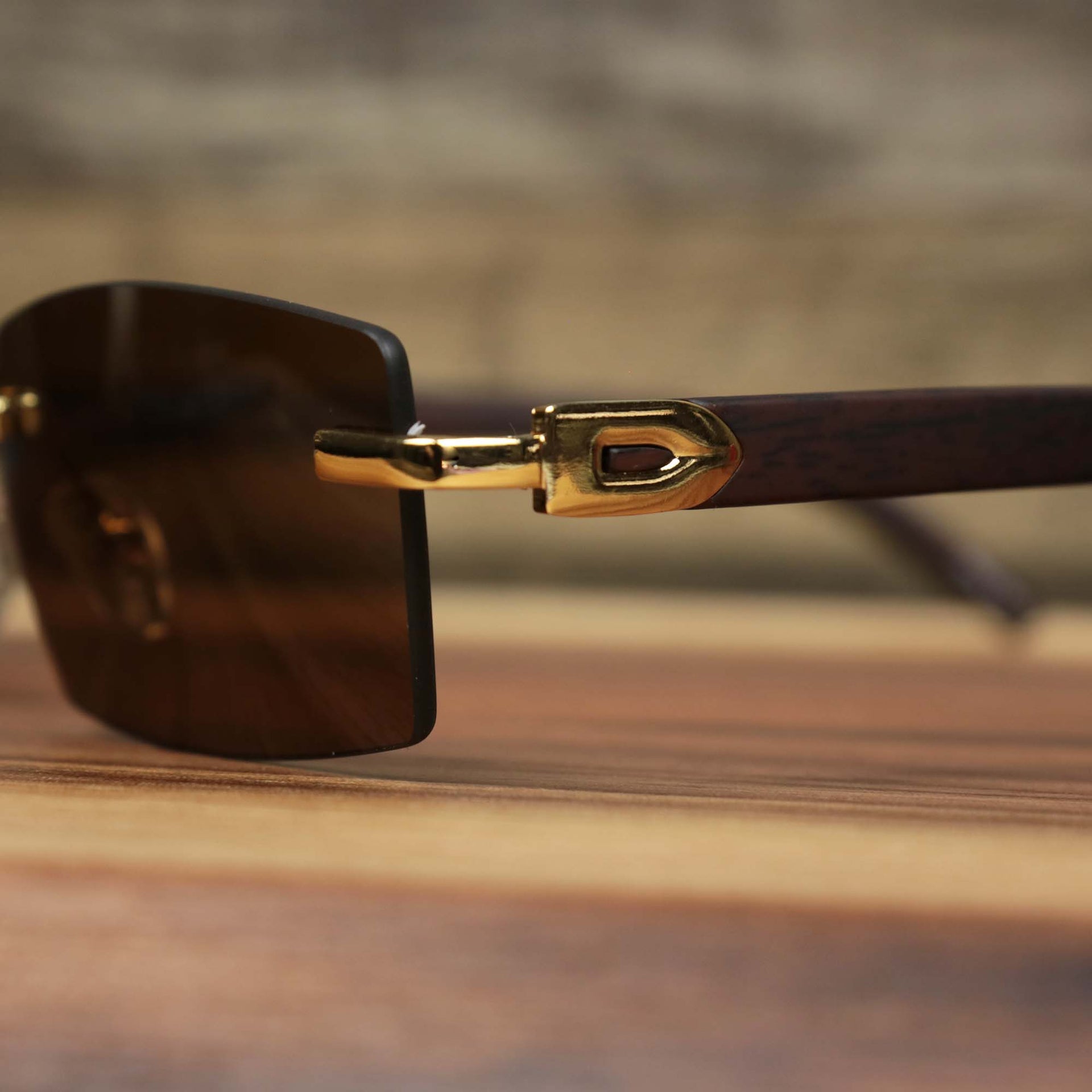 The hinge of the Rectangle Wood and Metal Frame Brown Lens Sunglasses with Gold Frame