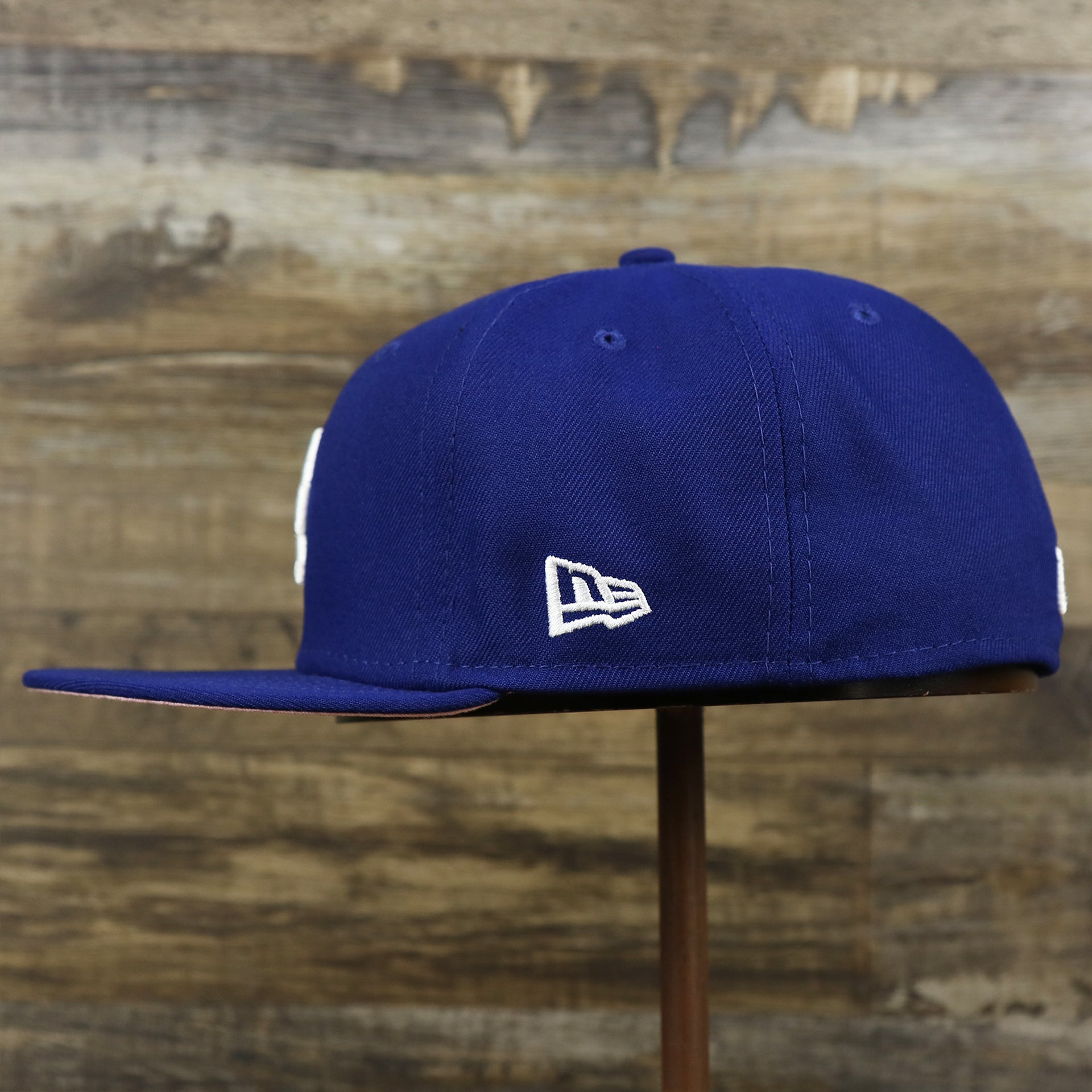 The wearer's left on the Los Angeles Dodgers Pop Sweat Pastel World Series Side Patch Fitted Cap With Pink Undervisor | Royal Blue 59Fifty Cap