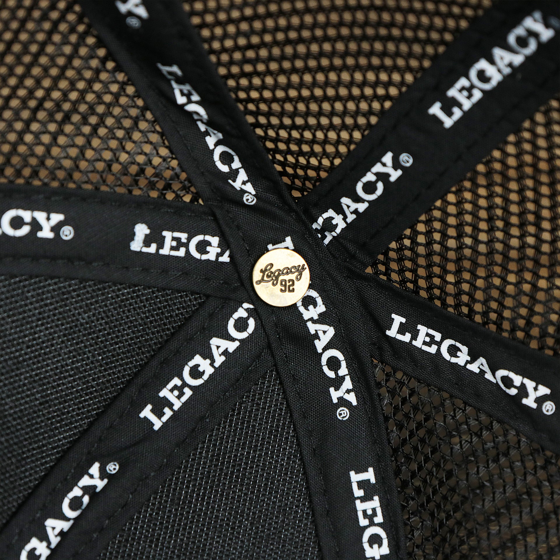 The Legacy Engraved Button on the Youth New Jersey Ocean City Sunset Mesh Back Trucker Hat | Black And Black Mesh Youth Trucker Hat