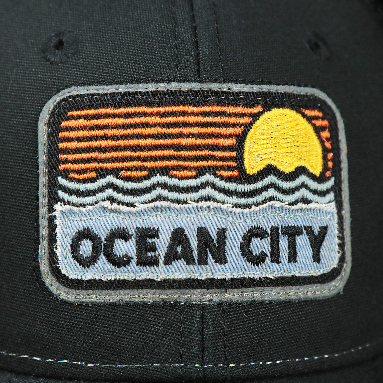 The Ocean City Sunset Patch on the Youth New Jersey Ocean City Sunset Mesh Back Trucker Hat | Black And Black Mesh Youth Trucker Hat