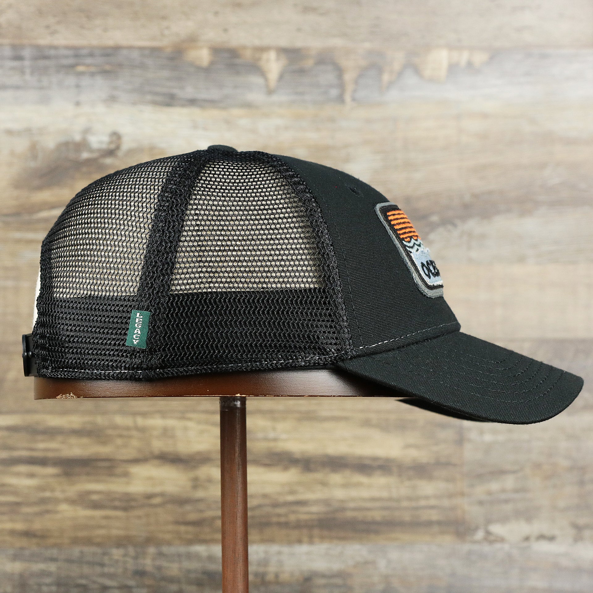 The wearer's right on the Youth New Jersey Ocean City Sunset Mesh Back Trucker Hat | Black And Black Mesh Youth Trucker Hat