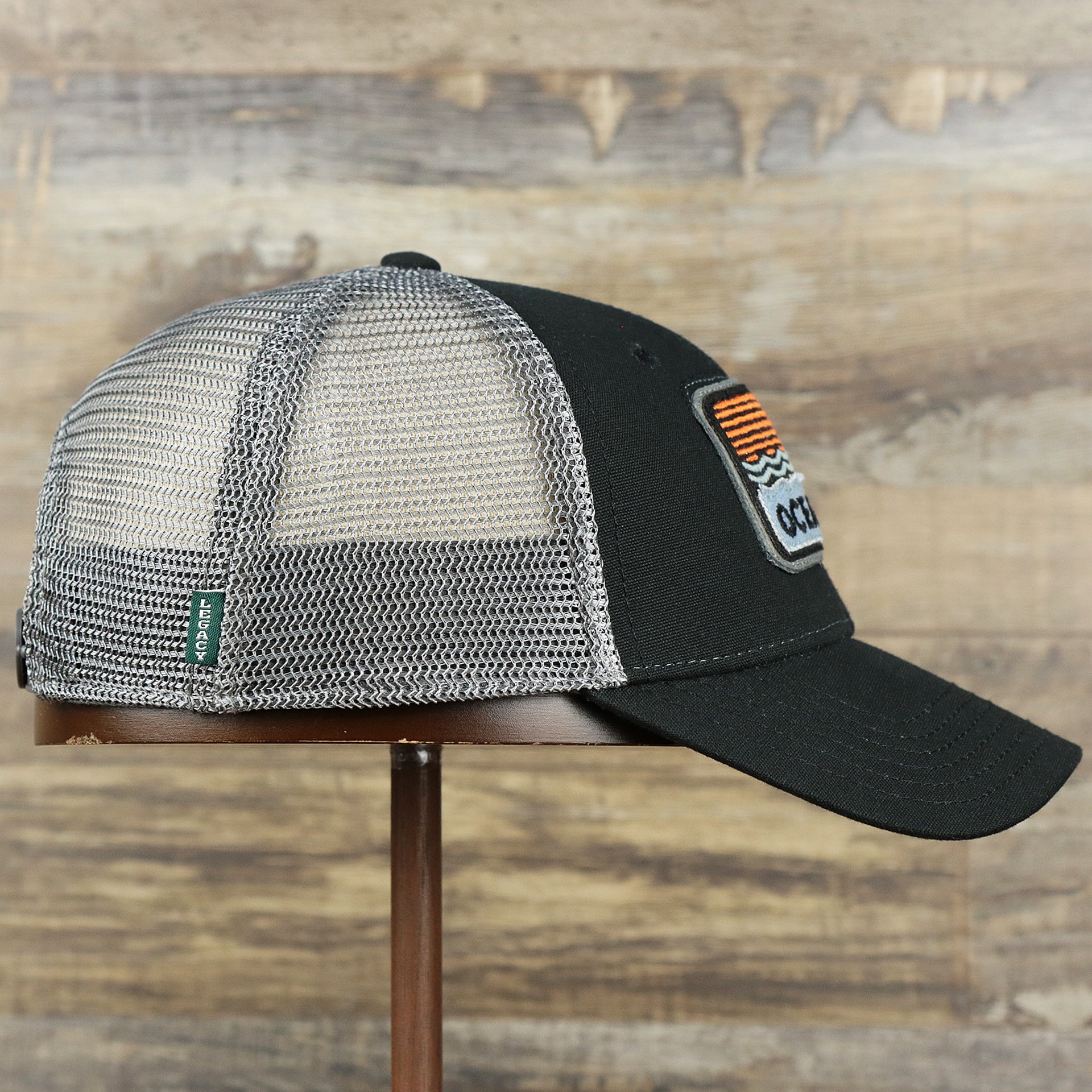 The wearer's right on the Youth New Jersey Ocean City Sunset Mesh Back Trucker Hat | Black And Grey Mesh Youth Trucker Hat