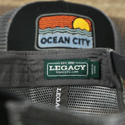 The Legacy Tag on the Youth New Jersey Ocean City Sunset Mesh Back Trucker Hat | Black And Grey Mesh Youth Trucker Hat