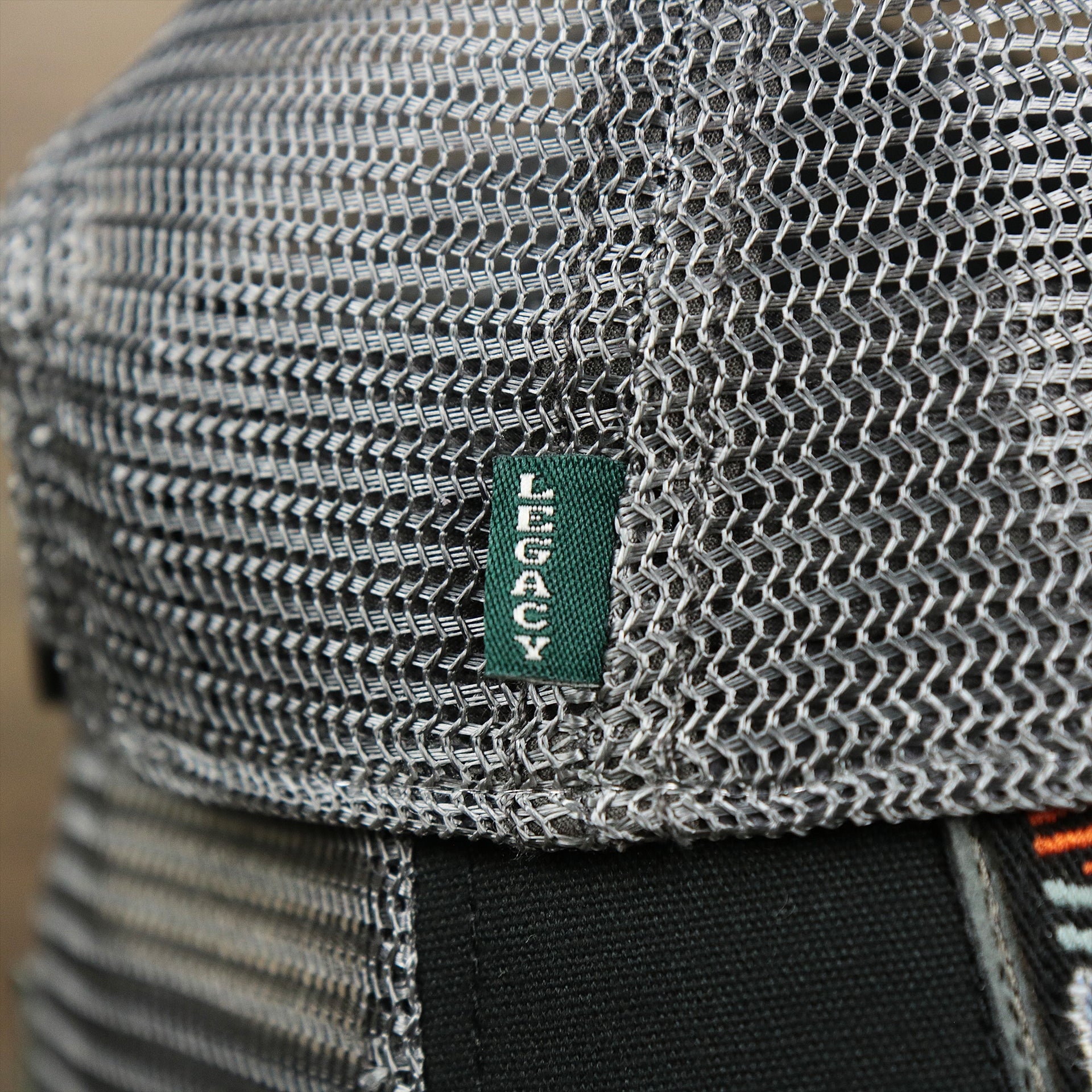 The Green Legacy Tag on the Youth New Jersey Ocean City Sunset Mesh Back Trucker Hat | Black And Grey Mesh Youth Trucker Hat