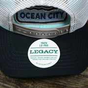 The Legacy Sticker on the New Jersey Ocean City Sunset Mesh Back Trucker Hat | Black And Grey Mesh Trucker Hat