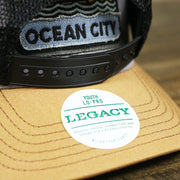 The Legacy Sticker on the Youth New Jersey Ocean City Sunset Mesh Back Trucker Hat | Gray And Black Mesh Youth Trucker Hat