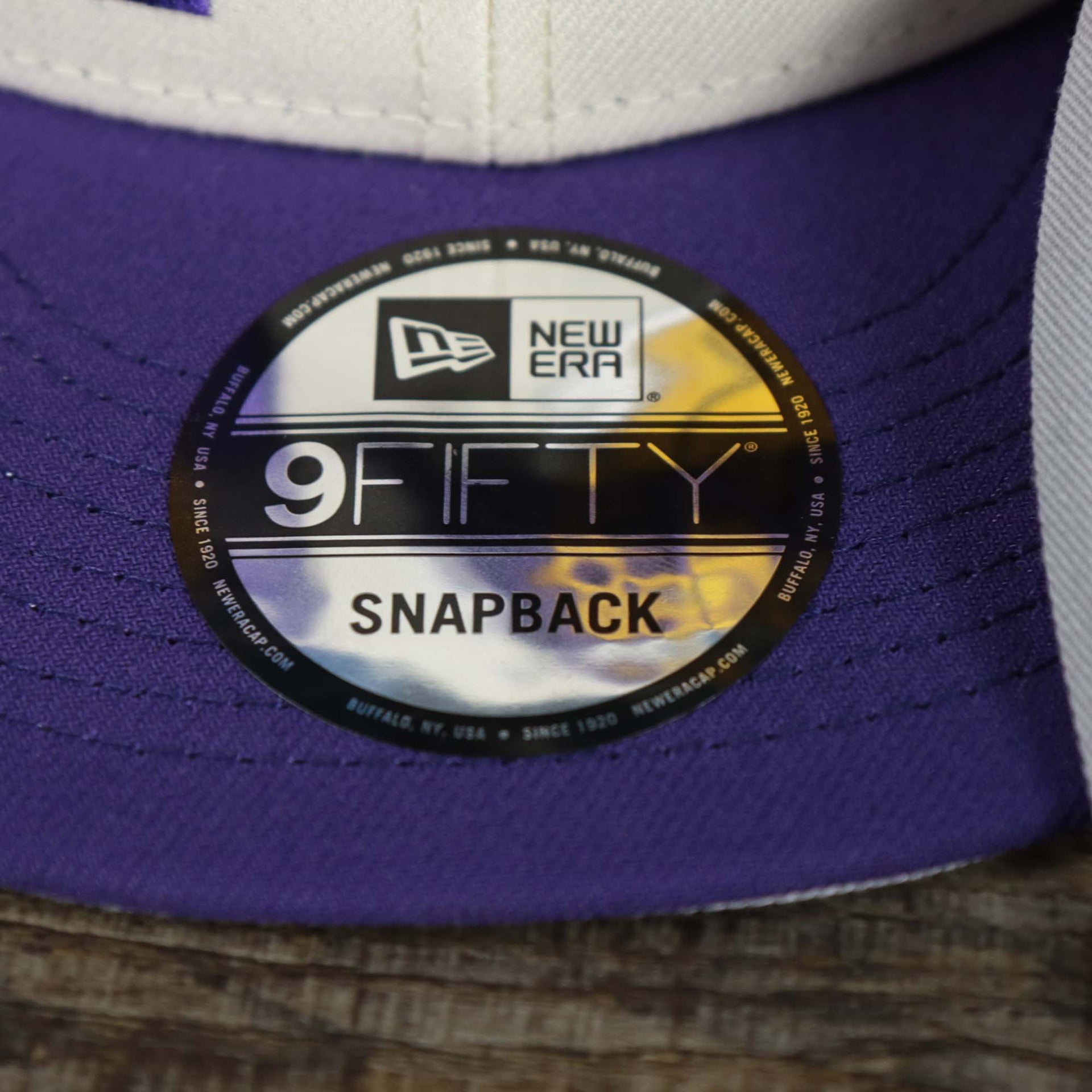 The 9Fifty Sticker on the Los Angeles Lakers NBA 2022 Draft Gray Bottom 9Fifty Snapback | New Era Cream/Purple