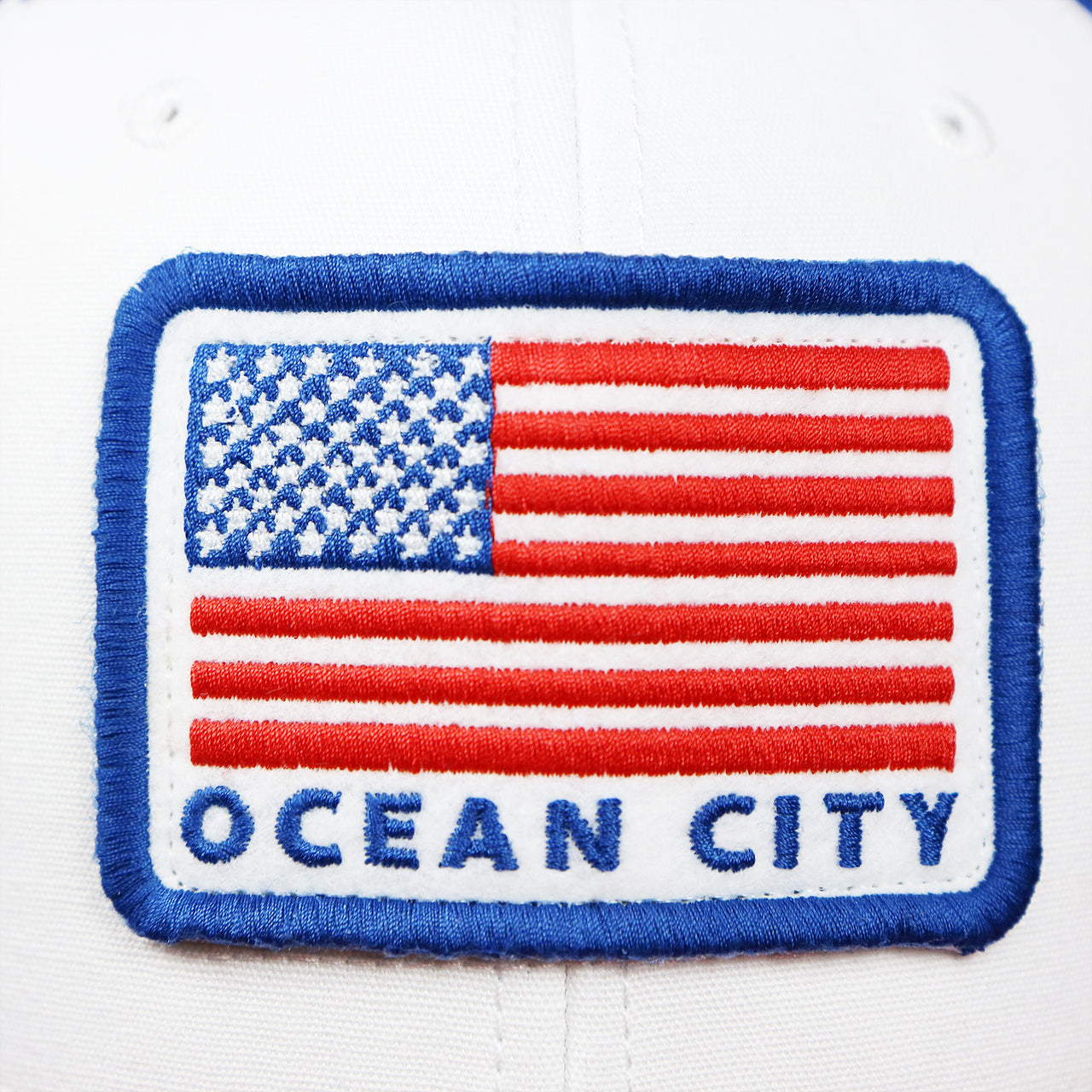 The Ocean City American Flag patch on the Ocean City Stars And Stripes USA Flag Royal Blue Mesh Trucker Hat | White And Royal Blue Trucker Hat