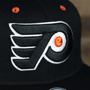 The Flyers Logo on the Philadelphia Flyers Side Patch Dugout Side Defender Fitted Cap | Black Stretch Fitted Cap