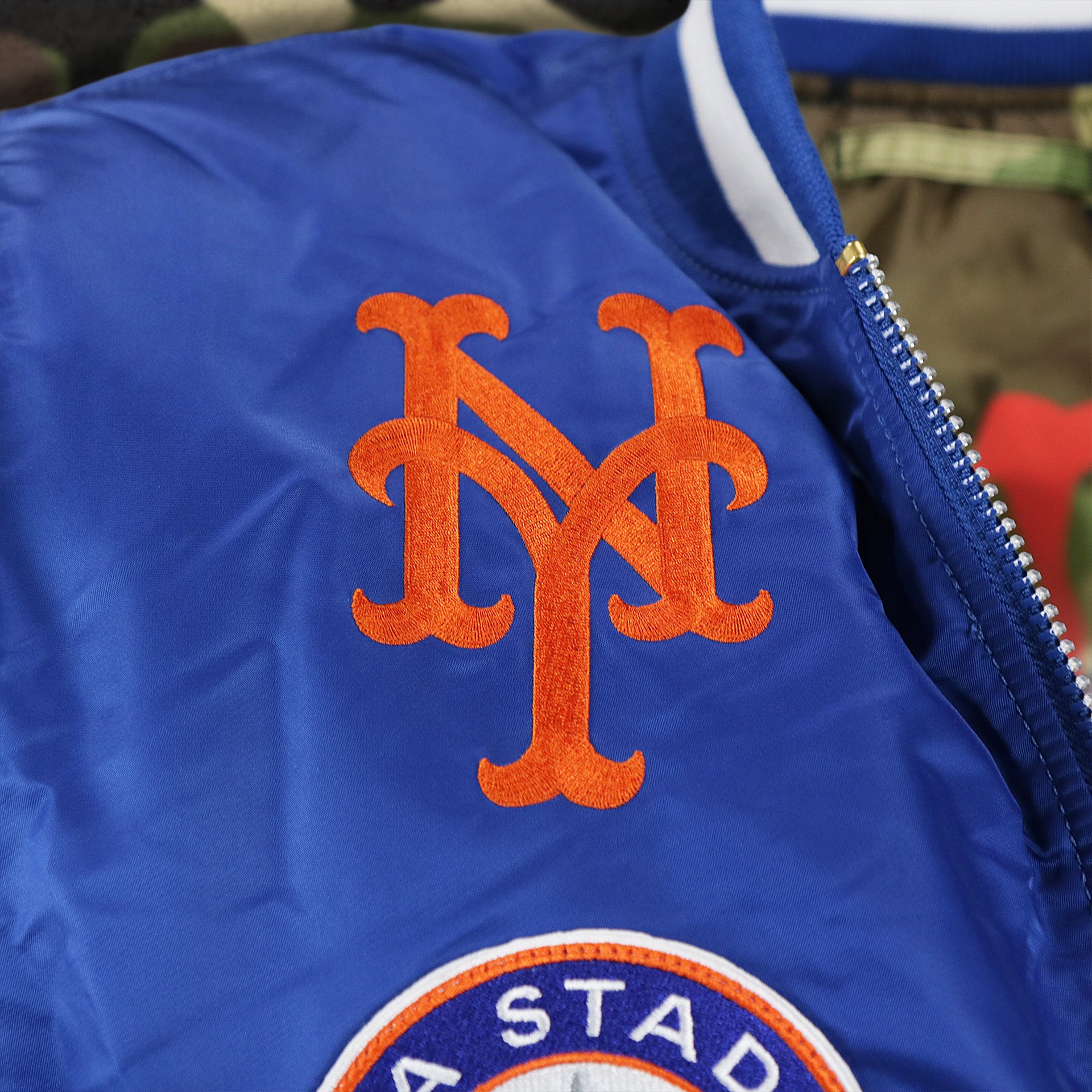 The New York Mets Logo Embroidered on the New York Mets MLB Patch Alpha Industries Reversible Bomber Jacket With Camo Liner | Royal Blue Bomber Jacket