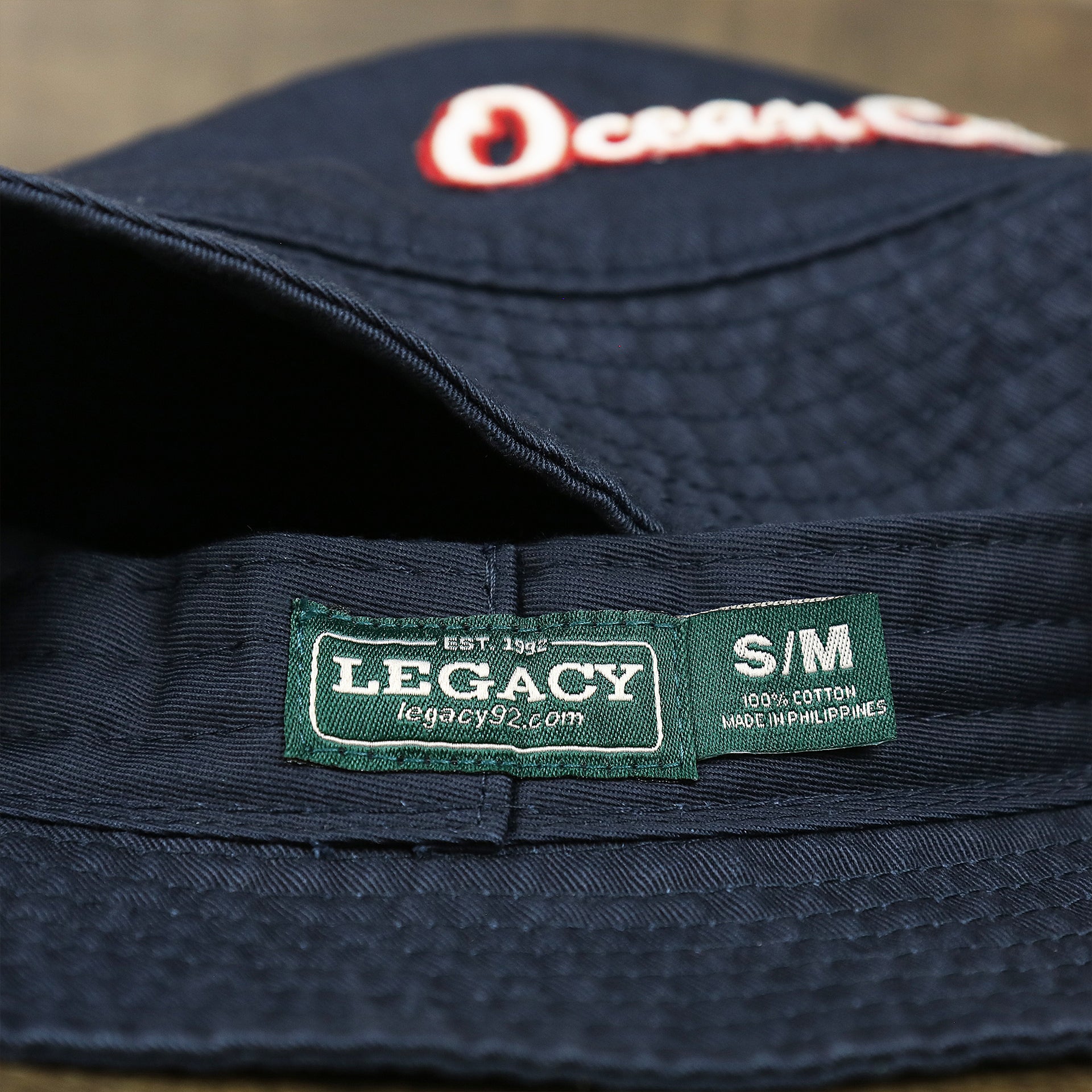The Legacy Tag on the White OCNJ Double Wordmark Red Outline Bucket Hat | Navy Bucket Hat