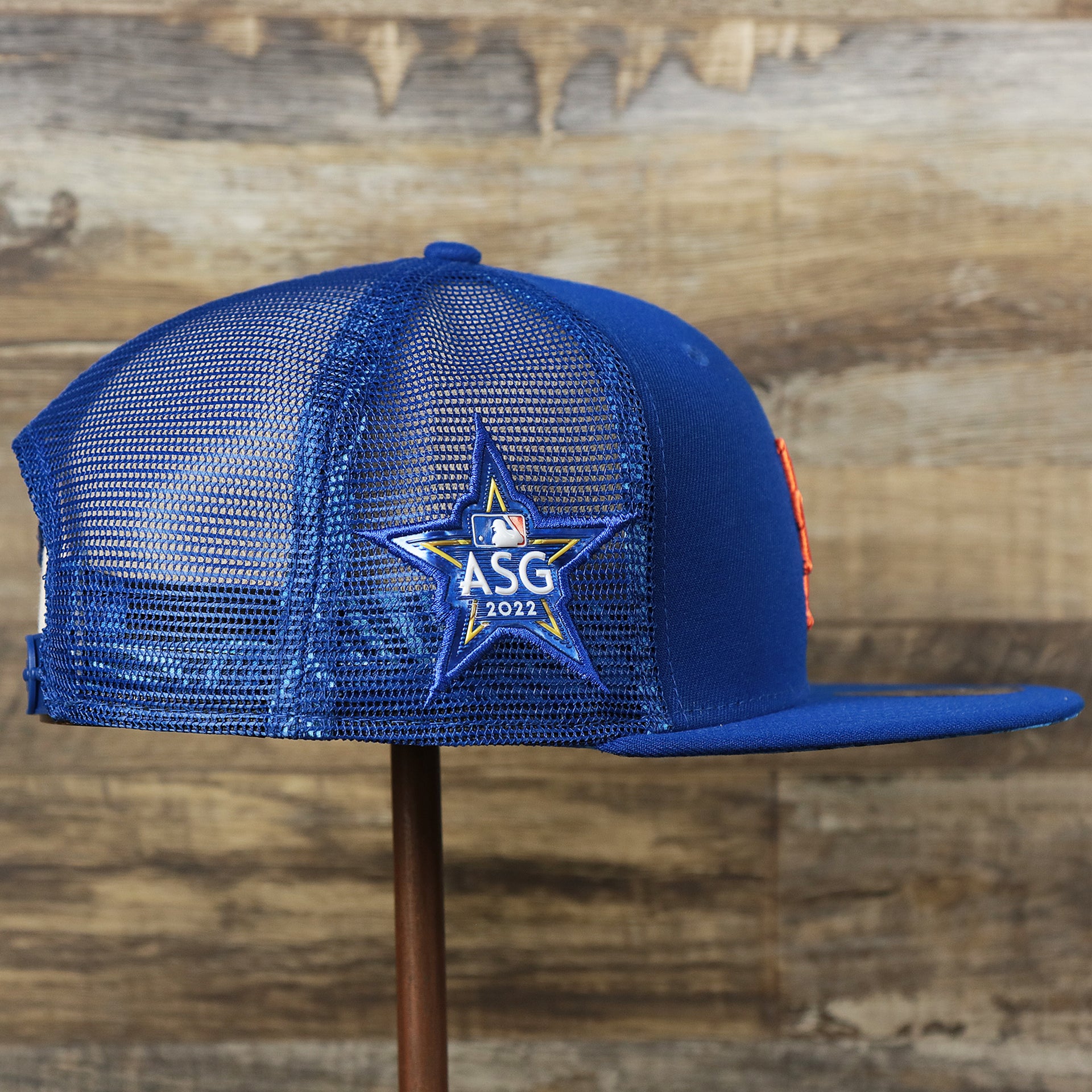 The wearer's right on the New York Mets Metallic All Star Game MLB 2022 Side Patch 9Fifty Mesh Snapback | ASG 2022 Royal Blue Trucker Hat