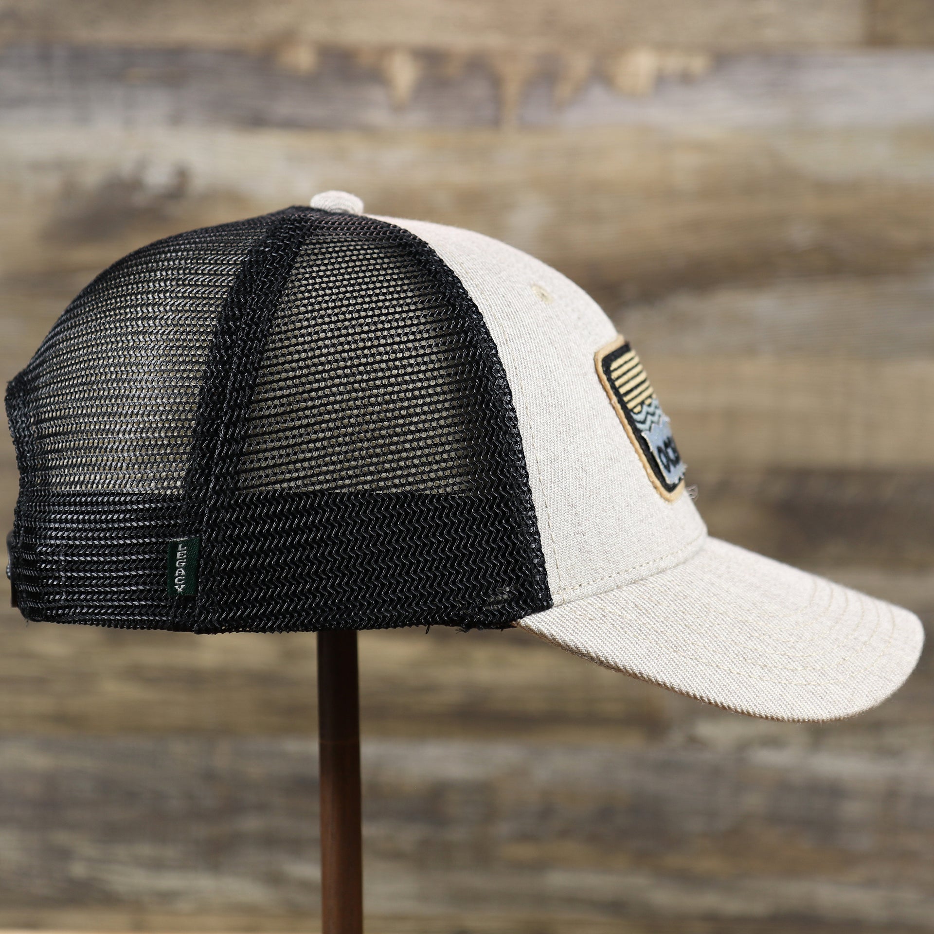 The wearer's right on the New Jersey Ocean City Sunset Mesh Back Trucker Hat | Heather Tan And Black Mesh Trucker Hat