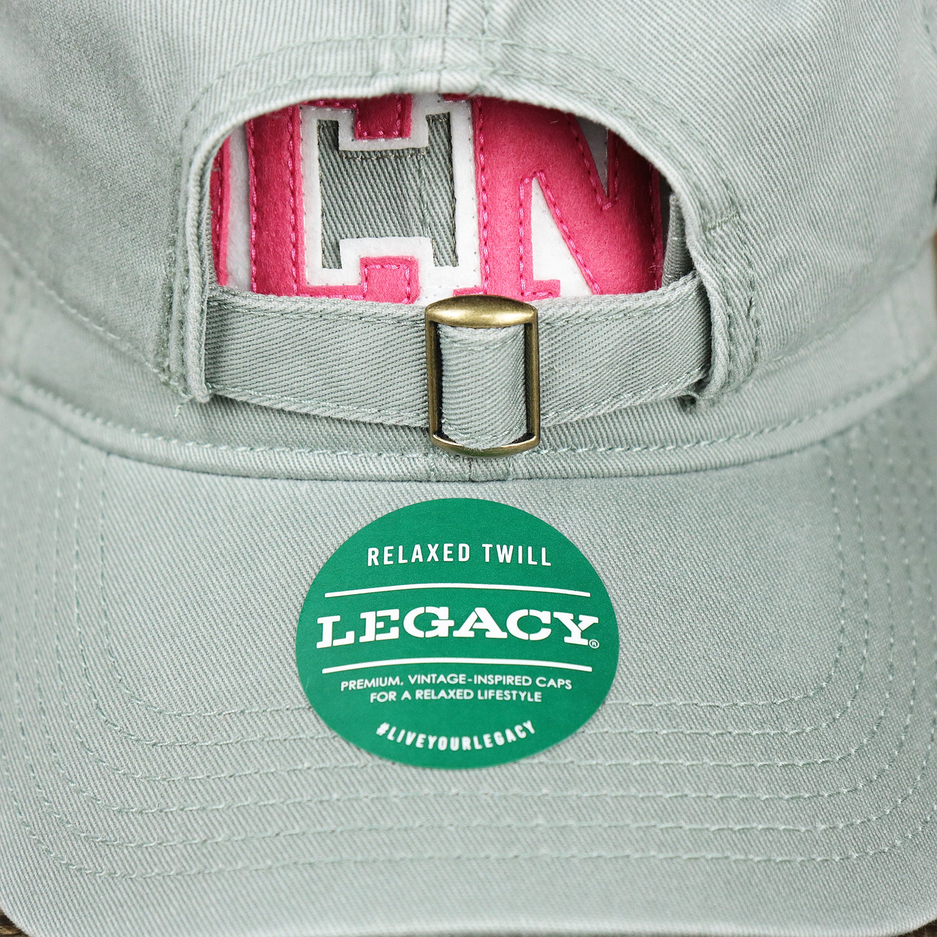 The Legacy Sticker on the Pink OCNJ Wordmark White Outline Dad Hat | Sawgrass Dad Hat