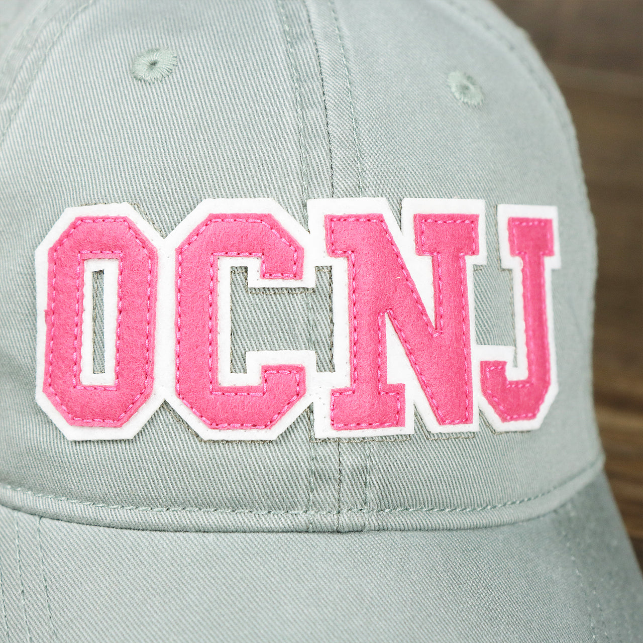 The OCNJ Wordmark on the Pink OCNJ Wordmark White Outline Dad Hat | Sawgrass Dad Hat