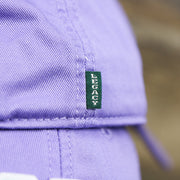 The Green Legacy Tag on the Teal OCNJ Double Wordmark White Outline Bucket Hat | Lavender Bucket Hat