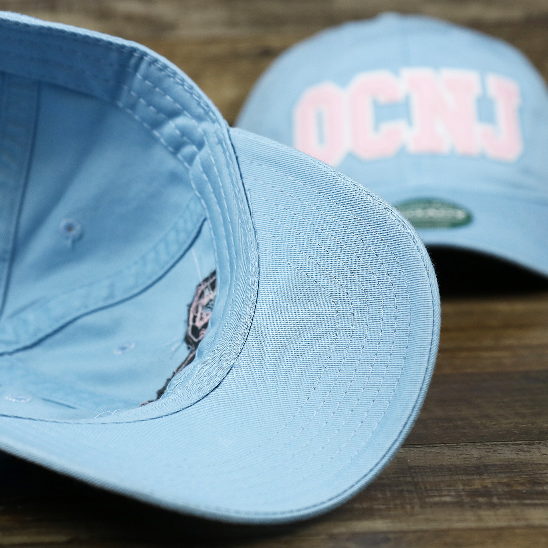 The undervisor on the Youth Pink OCNJ Wordmark White Outline Dad Hat | Youth Light Blue Dad Hat