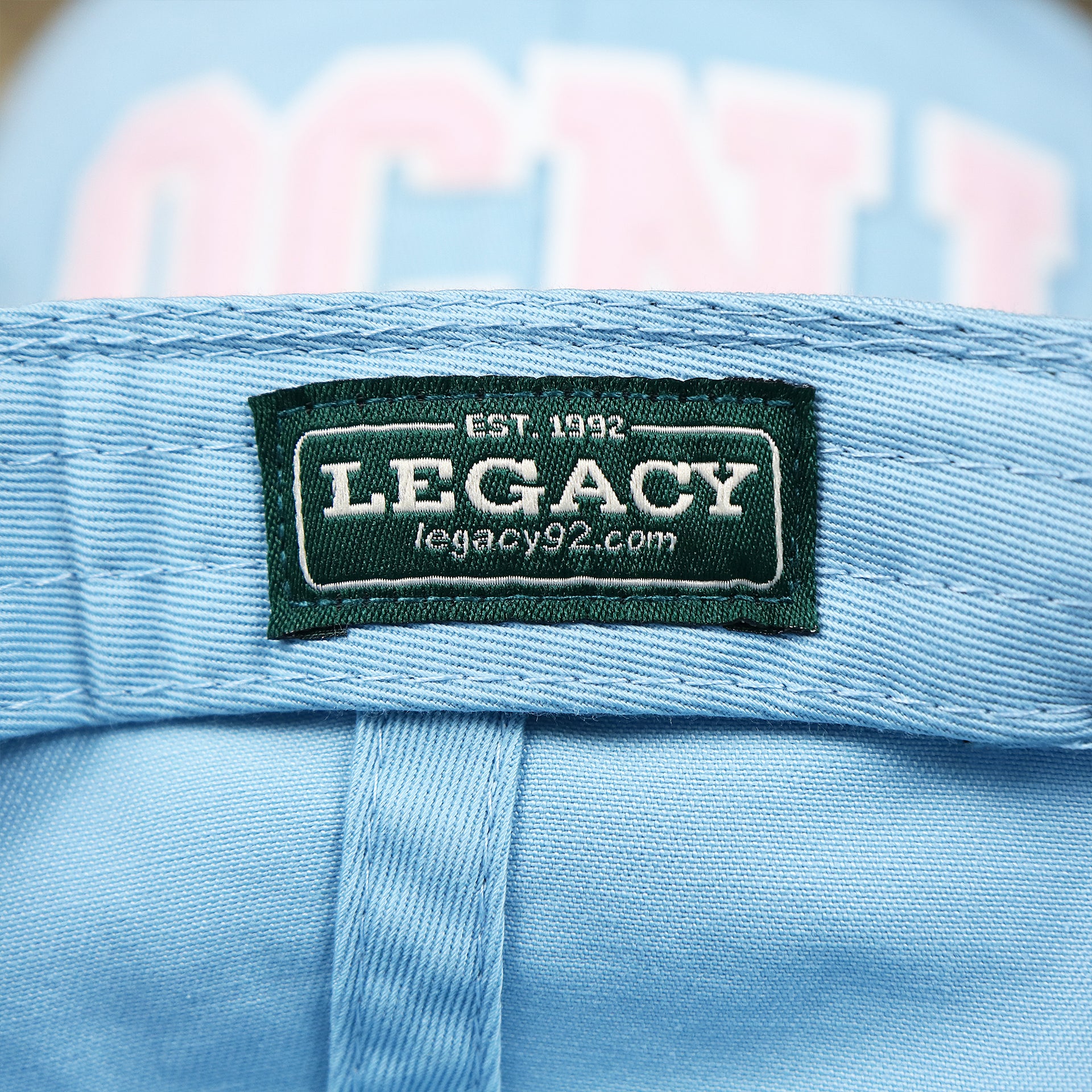 The Legacy Tag on the Youth Pink OCNJ Wordmark White Outline Dad Hat | Youth Light Blue Dad Hat