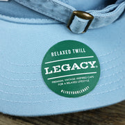 The Legacy Sticker on the Pink OCNJ Wordmark White Outline Dad Hat | Light Blue Dad Hat