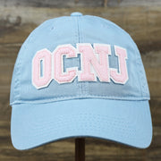 The front of the Youth Pink OCNJ Wordmark White Outline Dad Hat | Youth Light Blue Dad Hat