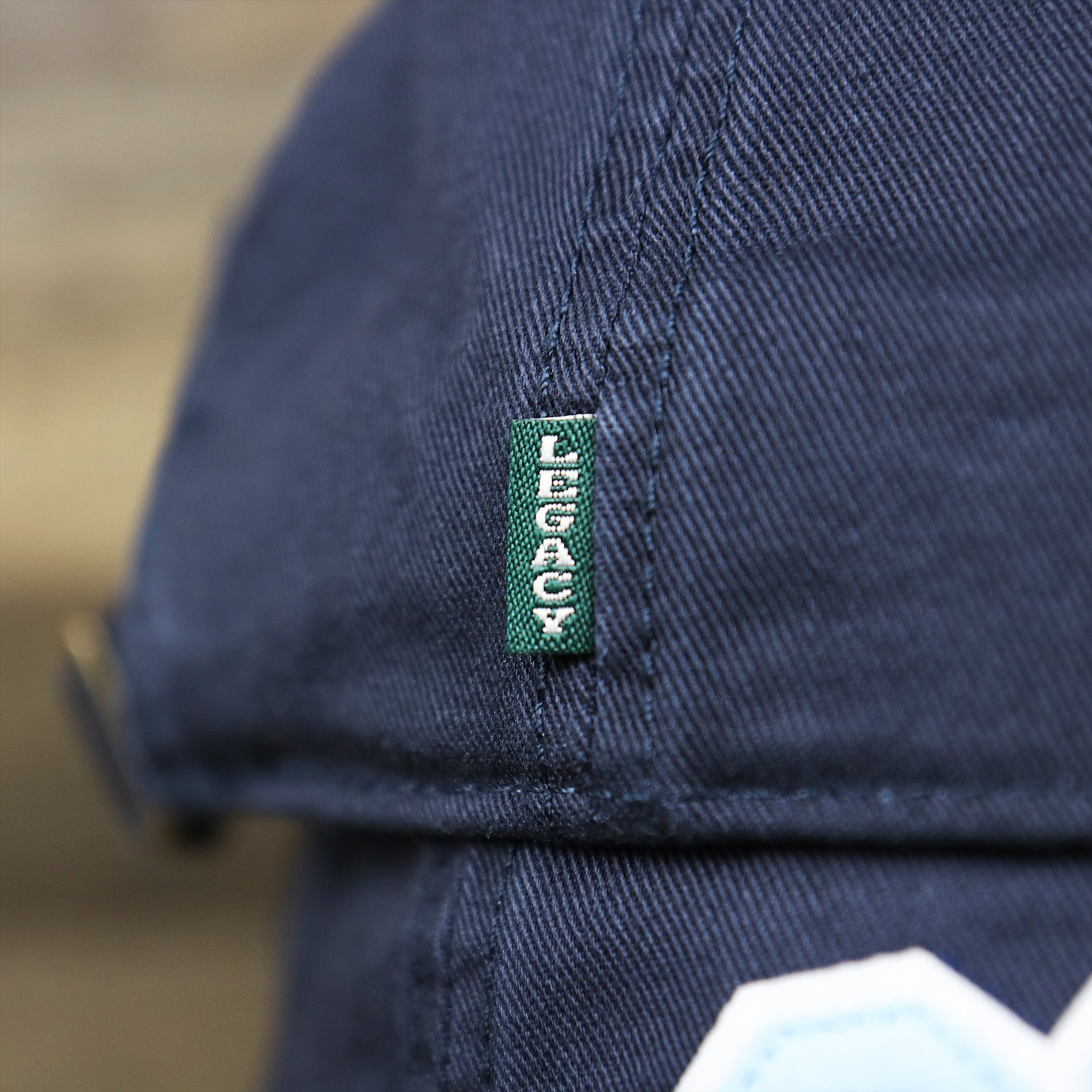 The Green Legacy Tag on the Youth Light Blue OCNJ Wordmark White Outline Dad Hat | Youth Navy Blue Dad Hat