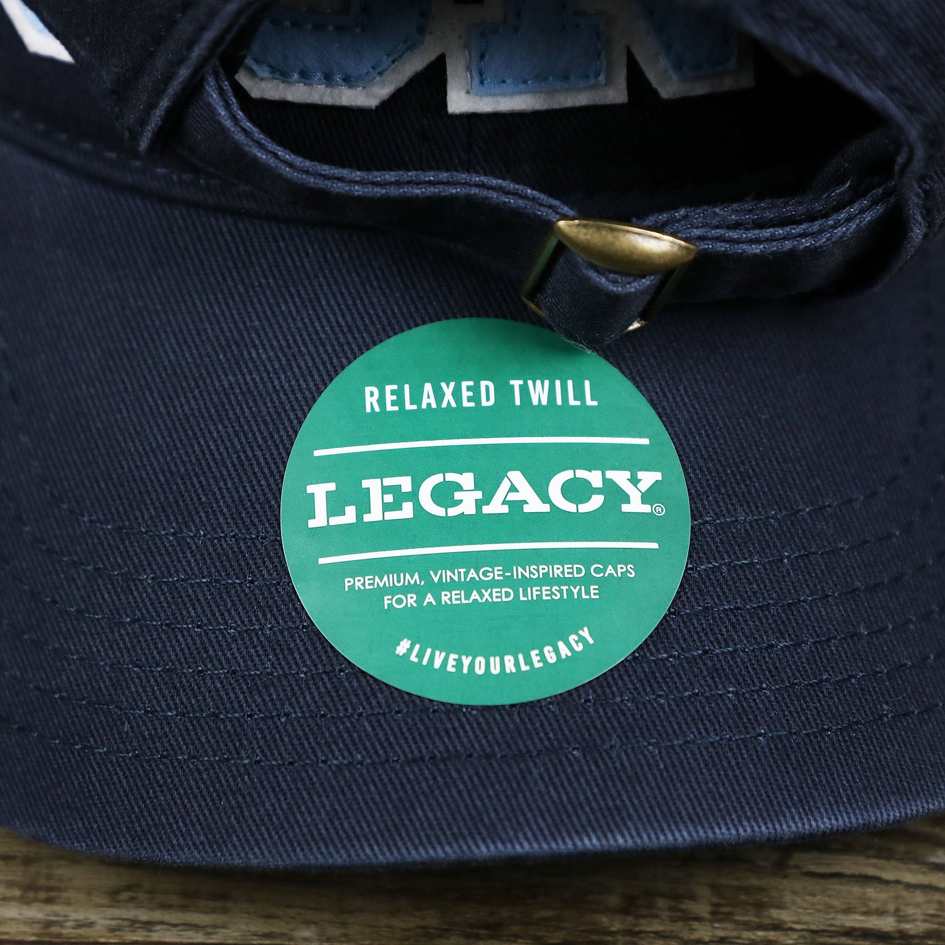 The Legacy Sticker on the Youth Light Blue OCNJ Wordmark White Outline Dad Hat | Youth Navy Blue Dad Hat
