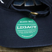 The Legacy Sticker on the Light Blue OCNJ Wordmark White Outline Dad Hat | Navy Blue Dad Hat