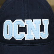 The OCNJ Wordmark on the Light Blue OCNJ Wordmark White Outline Dad Hat | Navy Blue Dad Hat