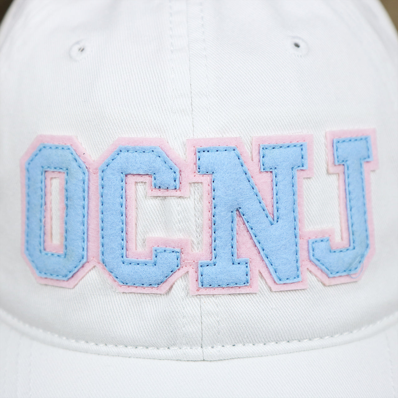 The OCNJ Wordmark on the Light Blue OCNJ Wordmark Pink Outline Dad Hat | White Dad Hat
