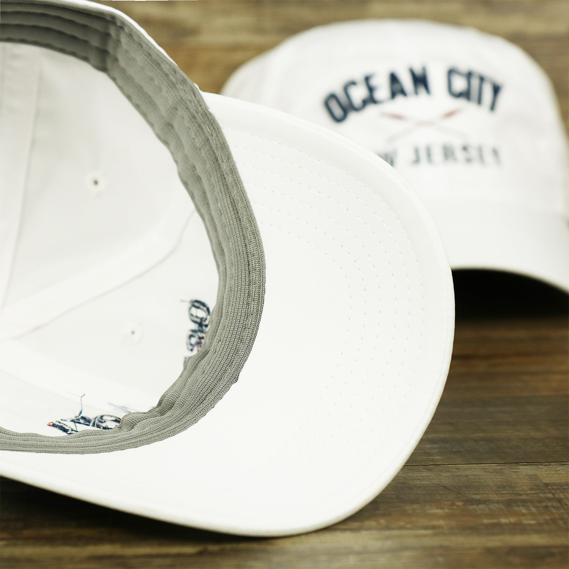 The undervisor on the Ocean City New Jersey Wordmark Crossed Oars Logo Dad Hat | White Dad Hat