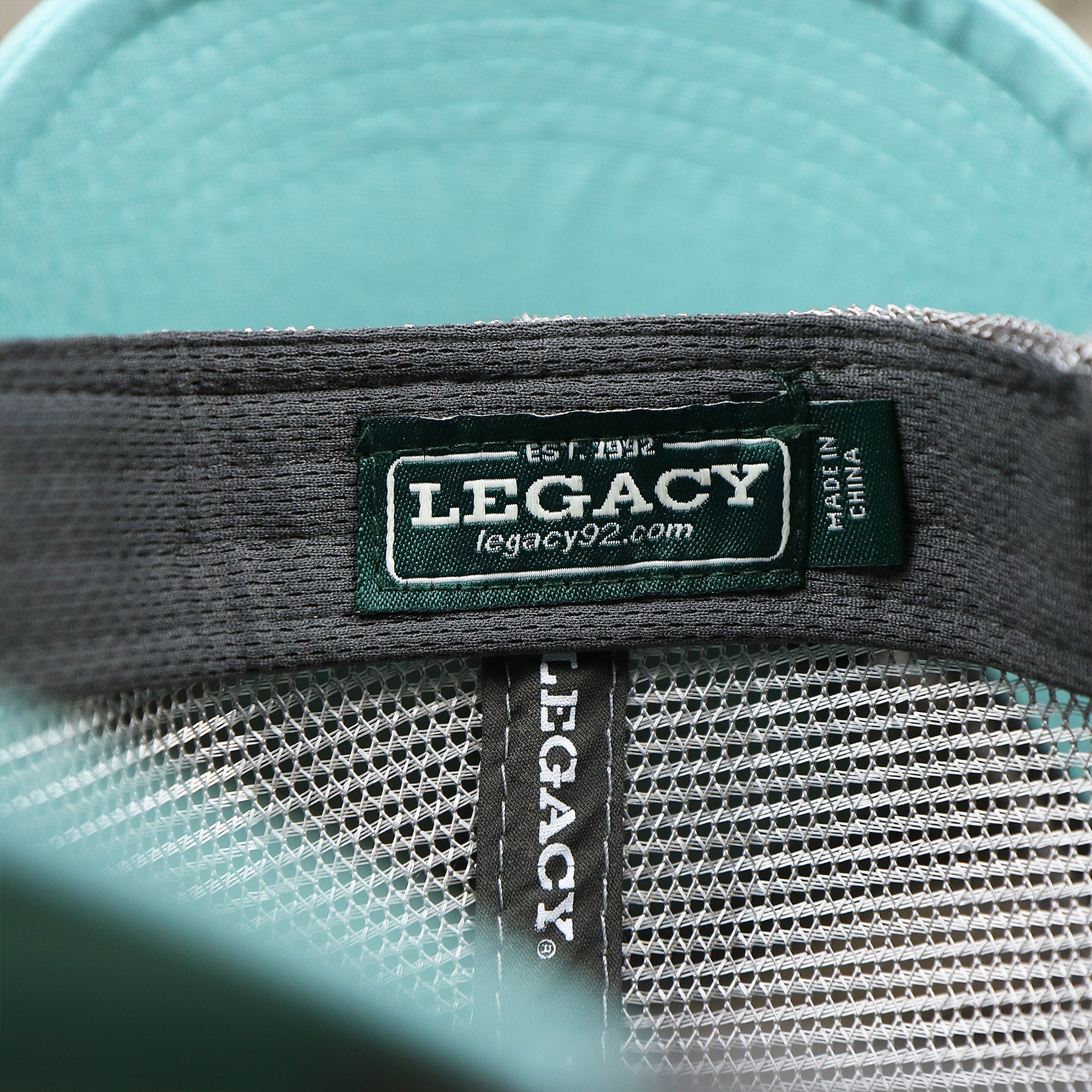 The Legacy Tag on the New Jersey Ocean City Sunset Mesh Back Trucker Hat | Tahiti Blue And Grey Mesh Trucker Hat