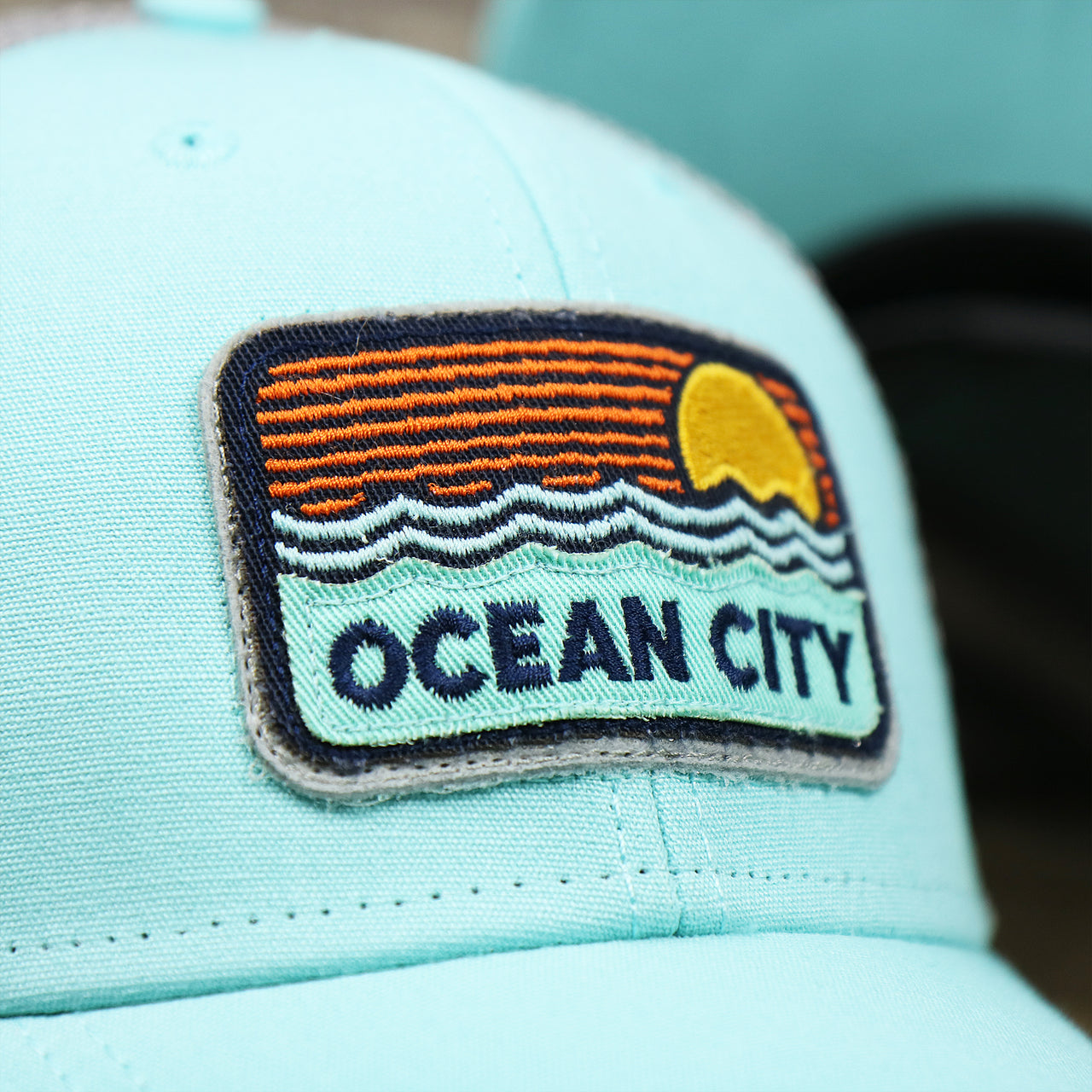 The OC Sunset Patch on the New Jersey Ocean City Sunset Mesh Back Trucker Hat | Tahiti Blue And Grey Mesh Trucker Hat