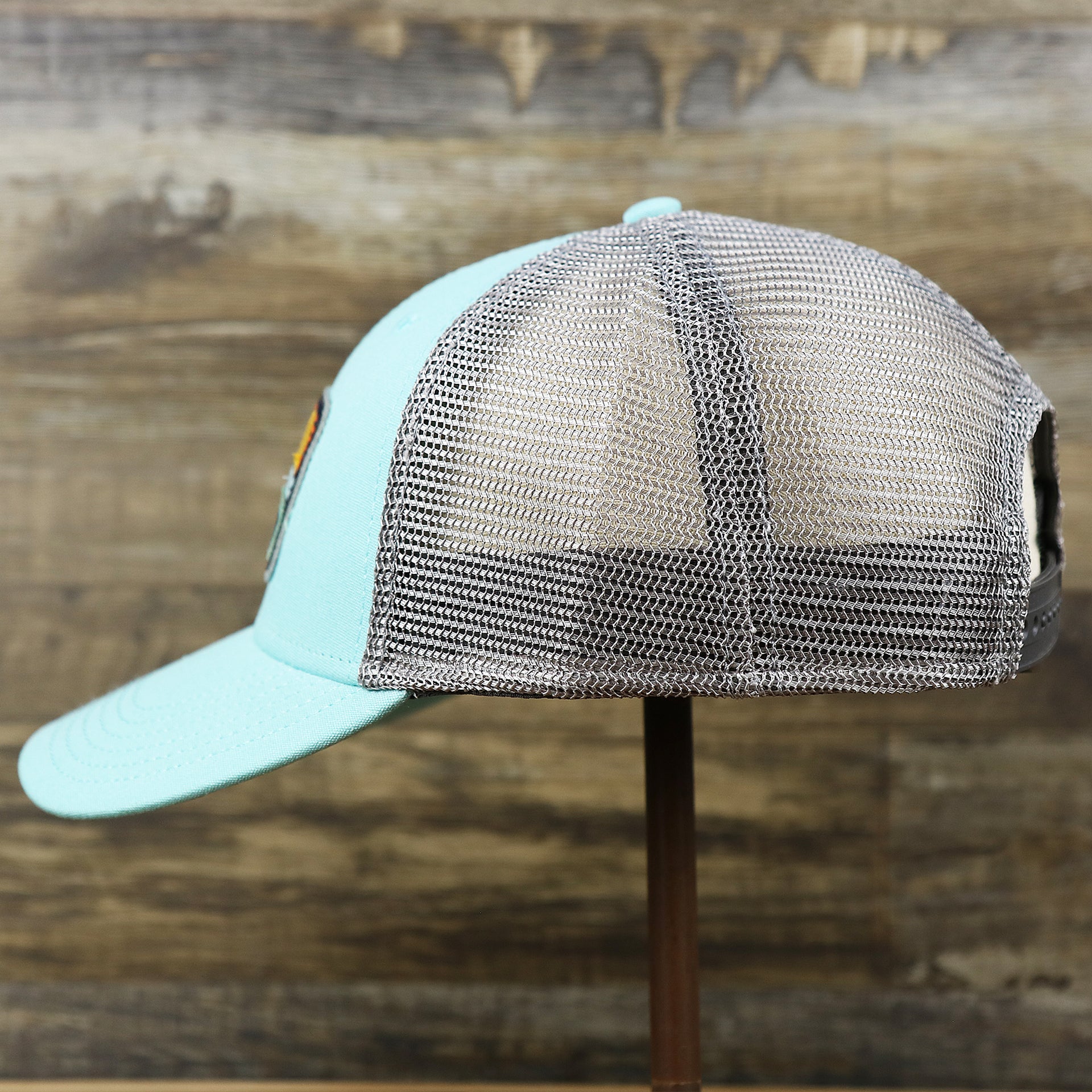 The wearer's left on the New Jersey Ocean City Sunset Mesh Back Trucker Hat | Tahiti Blue And Grey Mesh Trucker Hat