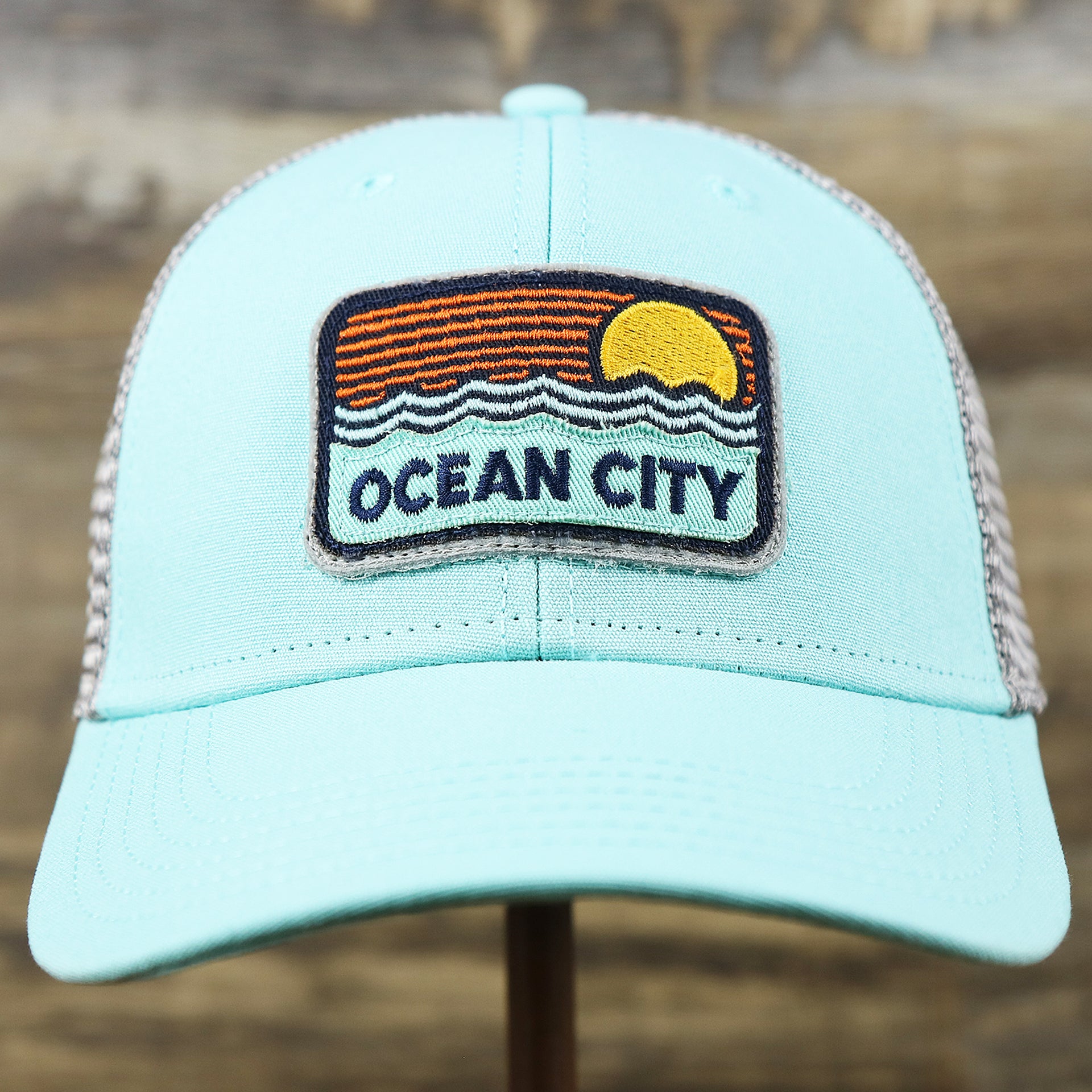 The front of the New Jersey Ocean City Sunset Mesh Back Trucker Hat | Tahiti Blue And Grey Mesh Trucker Hat