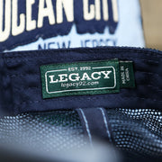 The Legacy Tag on the OCNJ Block Ocean City Wordmark Mesh Trucker Hat | Light Blue Trucker Hat