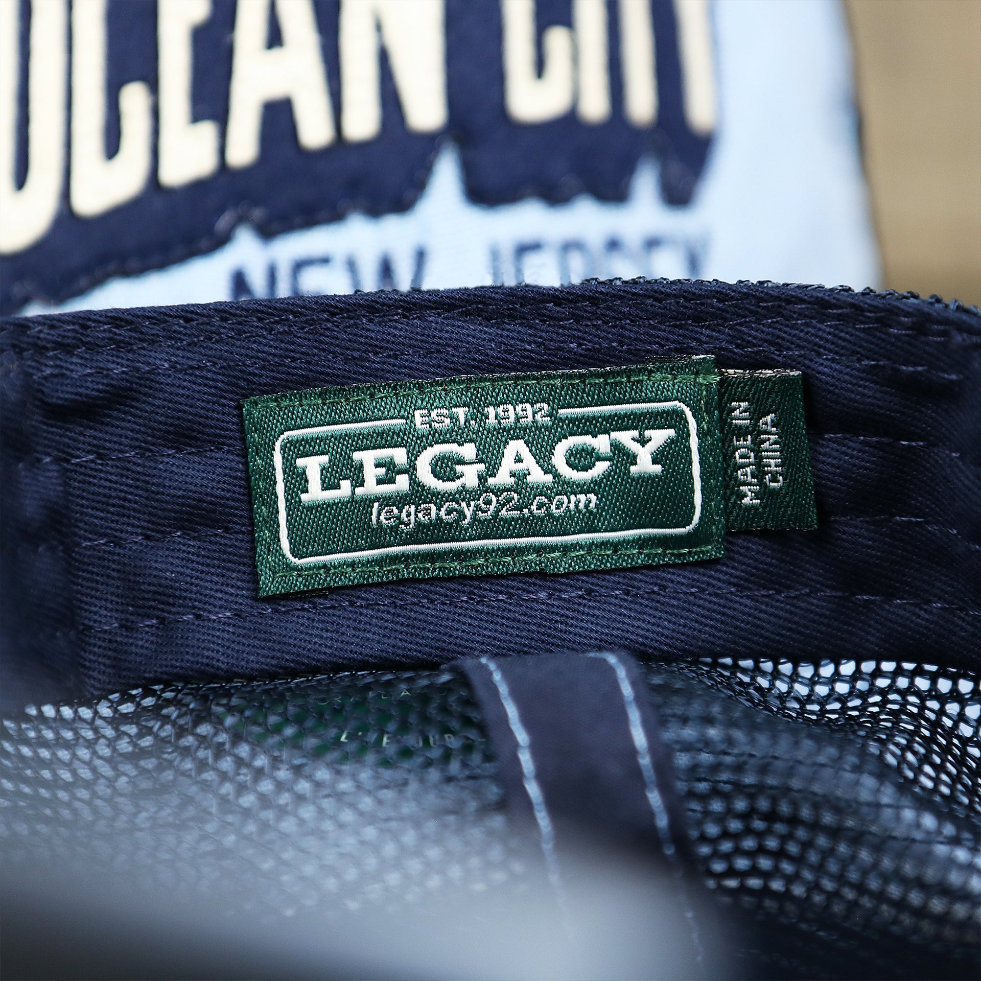 The Legacy Tag on the OCNJ Block Ocean City Wordmark Mesh Trucker Hat | Light Blue Trucker Hat