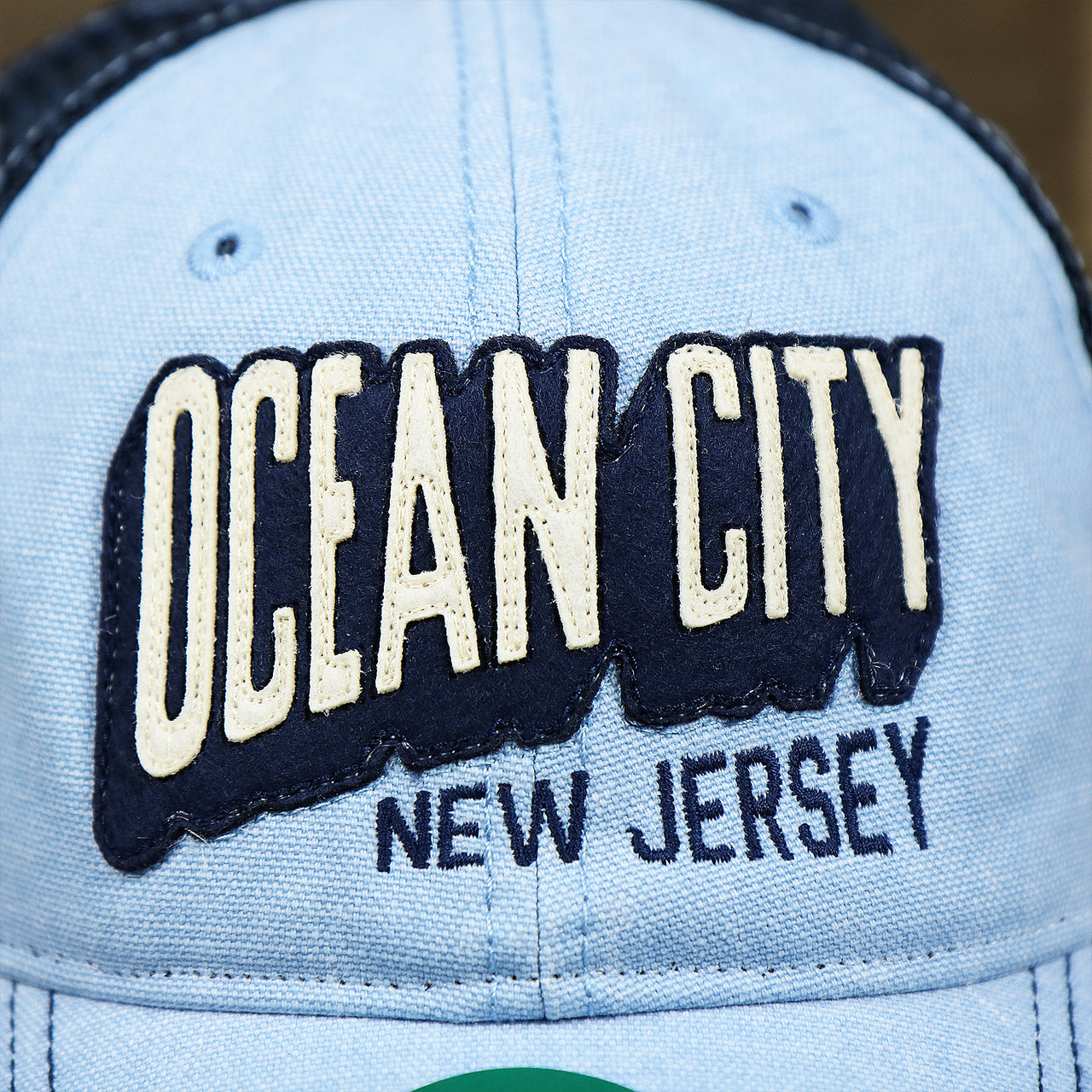 The OCNJ Wordmark on the OCNJ Block Ocean City Wordmark Mesh Trucker Hat | Light Blue Trucker Hat