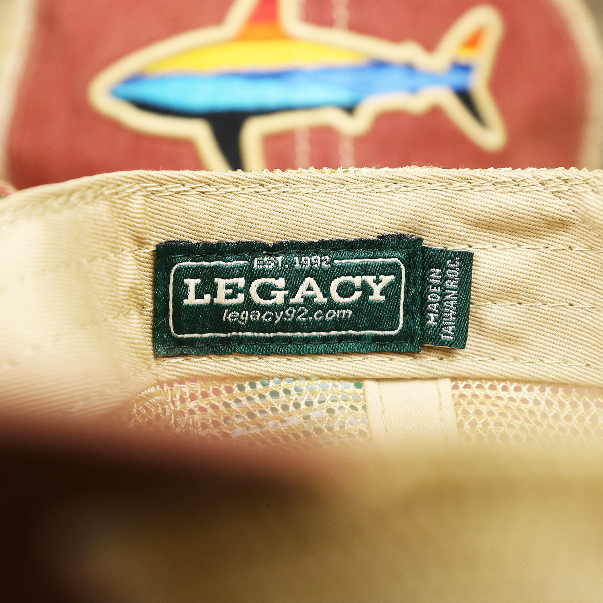 The legacy Tag on the Ocean City Horizon Shark Vintage Mesh Back Worn Colorway Trucker Hat | Cardinal Trucker Hat