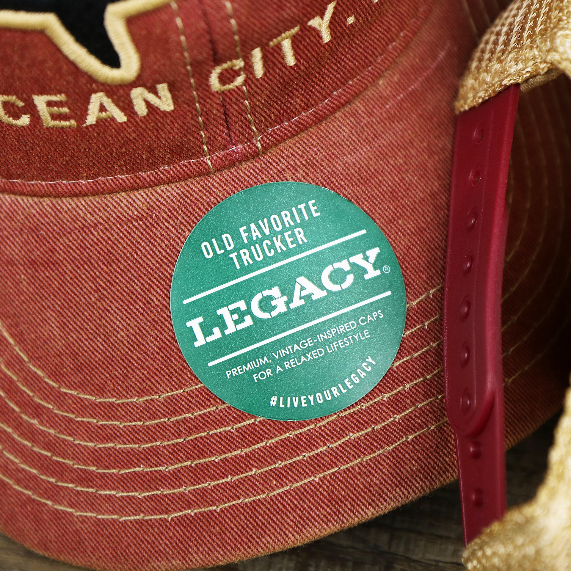 The Legacy Sticker on the Ocean City Horizon Shark Vintage Mesh Back Worn Colorway Trucker Hat | Cardinal Trucker Hat