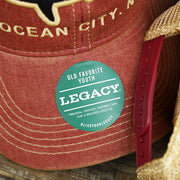 The Legacy Sticker on the Youth Ocean City Horizon Shark Vintage Mesh Back Worn Colorway Trucker Hat | Cardinal Trucker Hat