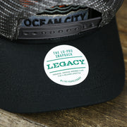 The Legacy Sticker on the Youth New Jersey Ocean City Sunset Mesh Back Trucker Hat | Tahiti Blue And Grey Mesh Trucker Hat