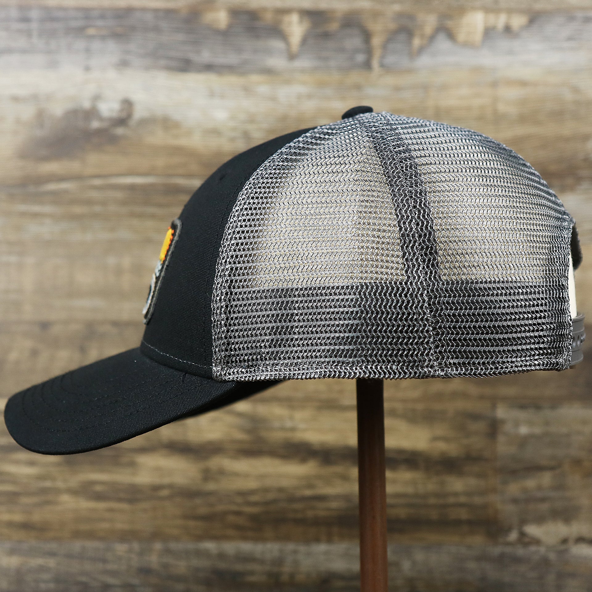 The wearer's left on the Youth New Jersey Ocean City Sunset Mesh Back Trucker Hat | Tahiti Blue And Grey Mesh Trucker Hat