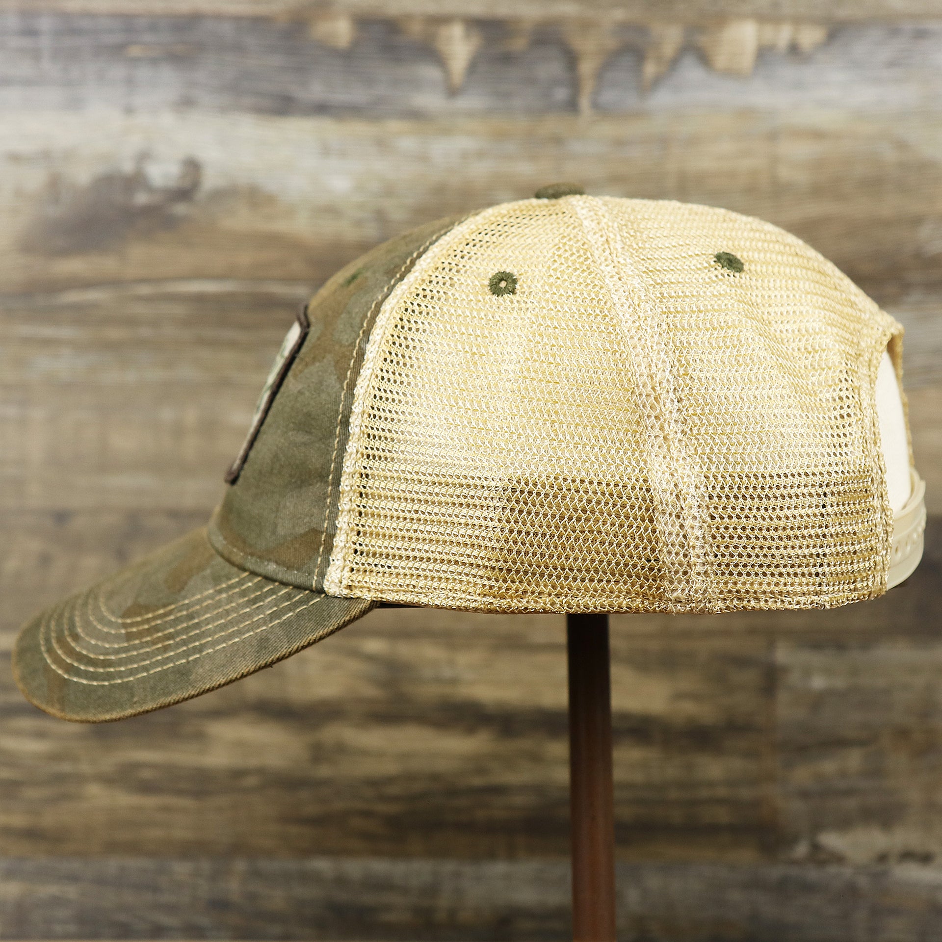 The wearer's left on the Ocean City New Jersey Since 1897 Helm Patch Camo Print Mesh Back Trucker Hat | Camo Green Trucker Hat