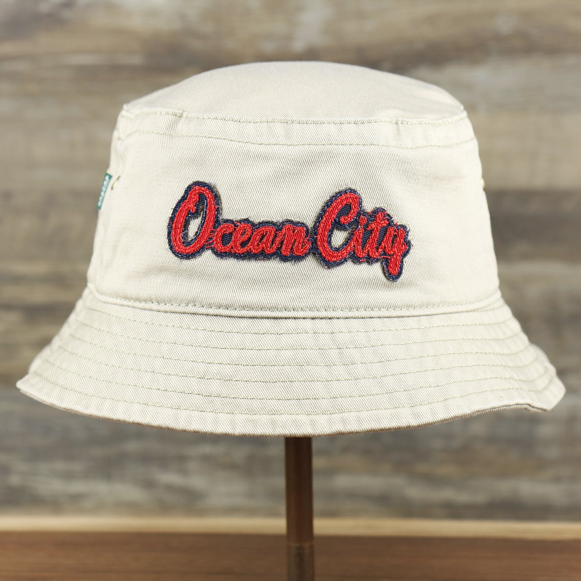 The front of the Red OCNJ Double Wordmark Navy Blue Outline Bucket Hat | Khaki Bucket Hat