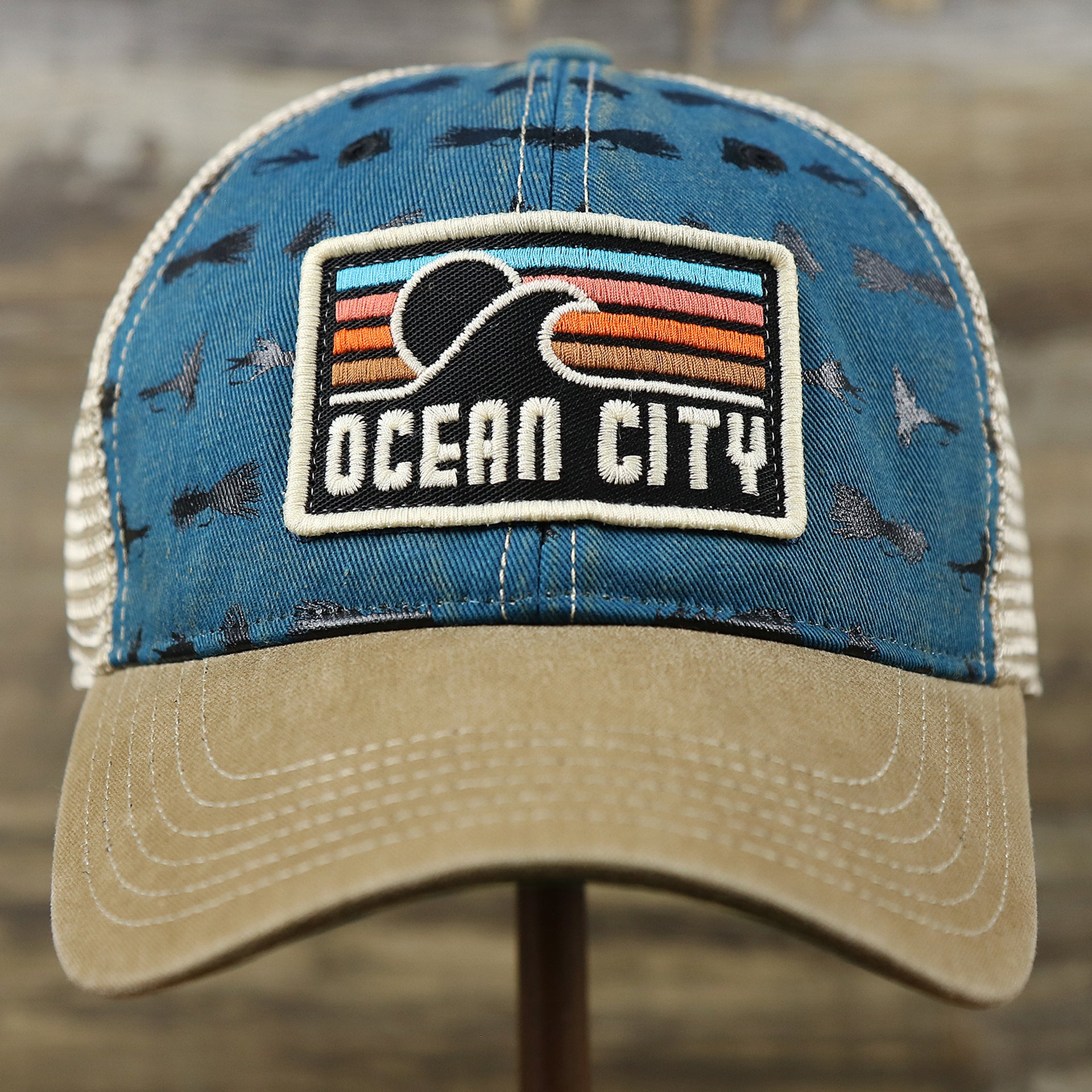 The front of the Ocean City Sunset Patch Fishing Lure Print Mesh Back Trucker Hat | Marine Blue Trucker Hat